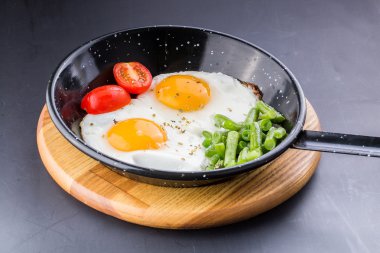 Sahanda yumurta domates ve kuşkonmaz eşliğinde bir Pan