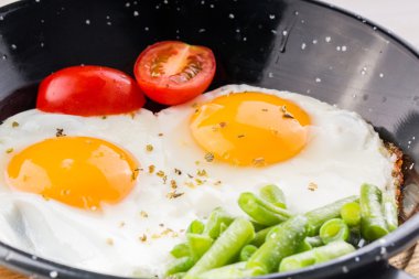 Sahanda yumurta domates ve kuşkonmaz eşliğinde bir Pan