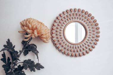 Dekoratif ayna ve sarı çiçek beyaz bir duvarda. ev dekoru