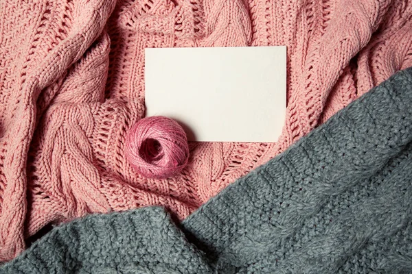 Bola de lã rosa com cartão branco para texto sobre fundo de malha rosa e cinza — Fotografia de Stock