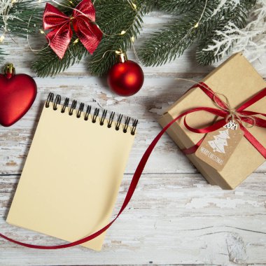 Noel süslemeleri ile ahşap arka planda sarmal not defteri ve hediye kutusu