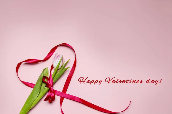 Tulipán y corazón hechos de cinta roja sobre un fondo rosa. Día de San Valentín — Foto de Stock