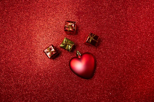 Cuore e piccole scatole regalo rosse su uno sfondo rosso. concetto di giorno di San Valentino — Foto Stock