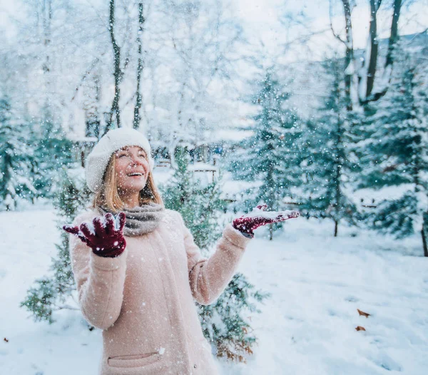 young girl laughs and throws snow in a winter snowy park. snow in the foreground