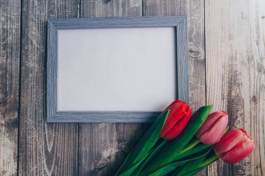 Ahşap bir arka planda fotoğraf çerçevesi ve pembe laleler. bahar konsepti 