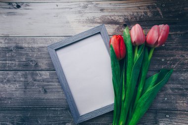 Ahşap bir arka planda fotoğraf çerçevesi ve pembe laleler. bahar konsepti 