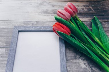 Ahşap bir arka planda fotoğraf çerçevesi ve pembe laleler. bahar konsepti 