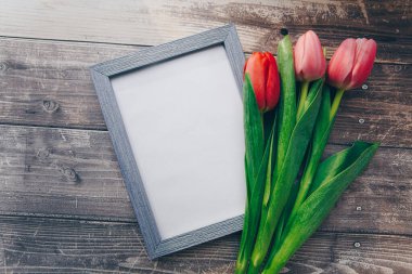 Ahşap bir arka planda fotoğraf çerçevesi ve pembe laleler. bahar konsepti 