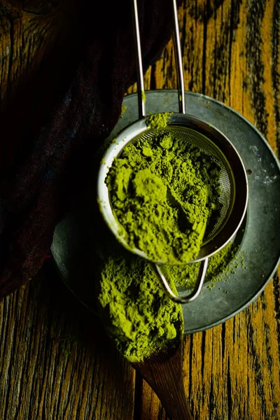 culinary grade green matcha tea powder in metal strainer cooking and baking ingredient