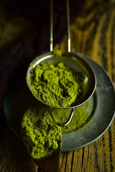 culinary grade green matcha tea powder in metal strainer cooking and baking ingredient