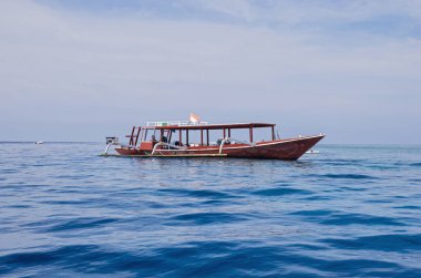 Tahta balıkçı teknesinin manzarası. Okyanusta güzel berrak su, arkada mavi gökyüzü.. 