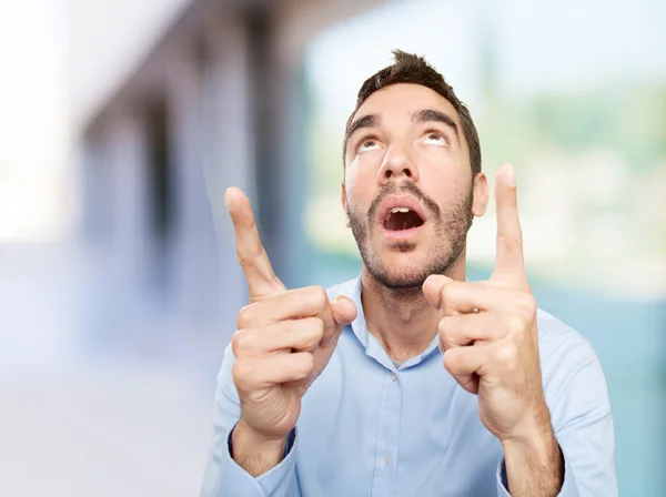 Close up of a surprised young man pointing up