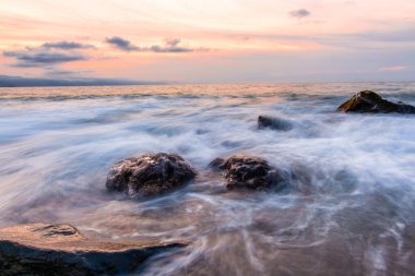 Kumsala dalgalar gibi dalgalı gökyüzü ile güzel bir okyanus batımı