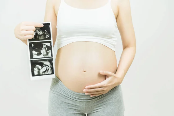 stock image A tummy of a pregnant woman with ultrasound images,Pregnancy health care preparing for baby concept.Motherhood among teenage mother, hugging belly, isolated on gray background