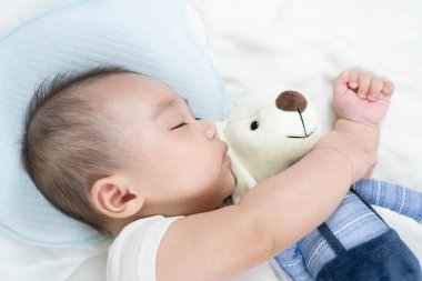 Uyuyan Charming bebeğinin seçici odak portresi Sevimli bebek rahat bir yatakta oyuncak bir ayıyla uyuyor