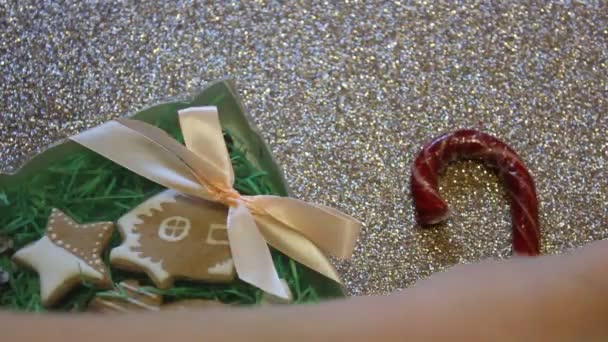 Kvinnliga händer slips gåva båge på en presentförpackning med ingefära kakor. Julklapp — Stockvideo