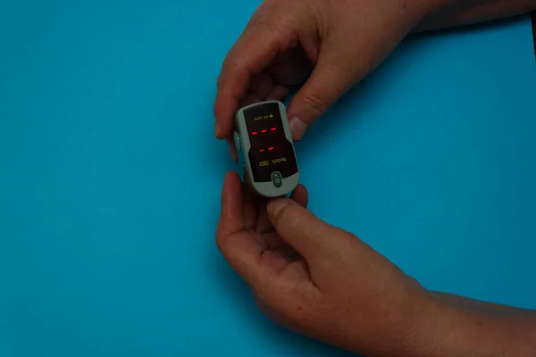 Hands of an elderly woman holding a pulse oximeter.measuring oxygen saturation with a pulse oximeter. Health concept. — Stock Photo, Image