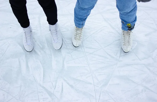 Närbild av kvinnliga fötter skridskoåkning på vintern på en utomhus ishall. Skridskor för två vänner skridskor tillsammans på en vinterdag. Vintertid, friluftsliv, vinterfritid Royaltyfria Stockbilder