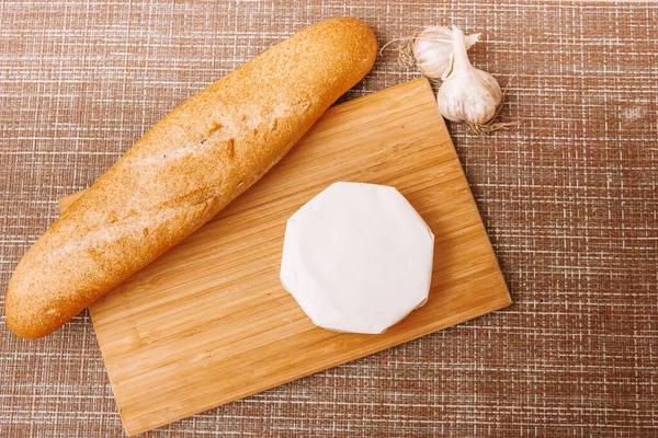 Formaggio ammuffito su una confezione di carta. camembert in carta bianca confezionamento sul tavolo della cucina — Foto Stock