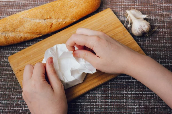 DIY испек сыр camembert инструкция шаг за шагом. шаг 1 распаковка камамбера в белую бумажную упаковку. — стоковое фото