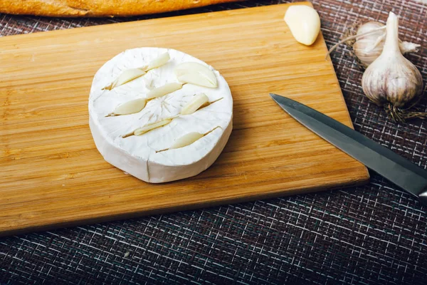 DIY queso horneado camembert instrucción paso a paso. paso 2 hacer cortes en el camembert e insertar el ajo en los cortos.queso con queso moldeado blanco — Foto de Stock