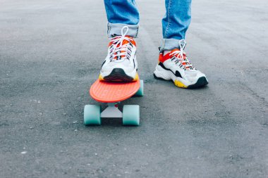 Parkta bozuk para tahtasıyla duran yırtık kotlu genç adam. yaz aktiviteleri kaykay