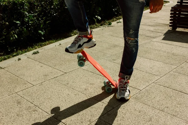 Junger Mann in zerrissenen Jeans steht mit Penny-Board im Park. Sommeraktivitäten Skateboarden — Stockfoto