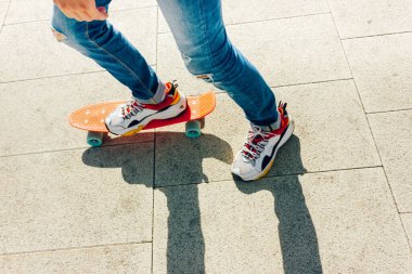 Parkta bozuk para tahtasıyla duran yırtık kotlu genç adam. yaz aktiviteleri kaykay.