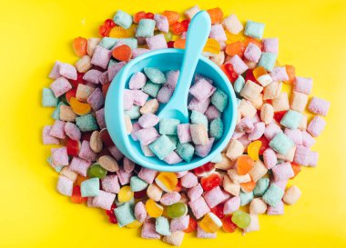 Çocuk sofra takımı, kaşıklı silikon kase. Bebek maması, çocuk maması. Mavi silikon kase ve kaşık bir yığın şeker ve marmelat içinde. Parlak, renkli bir fotoğraf.