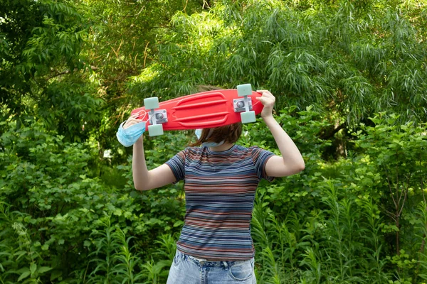 De cerca chica con estilo que lleva el tablero de peniques en el fondo de los árboles verdes — Foto de Stock