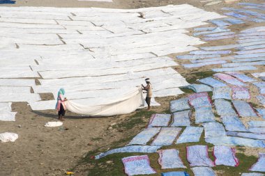 Agra, Hindistan - 15 Şubat 2018: Kimliği belirsiz insanlar Yanuma Agra nehrinin kıyısında sıcak güneşte yıkandıktan sonra bez kurutuyorlar 