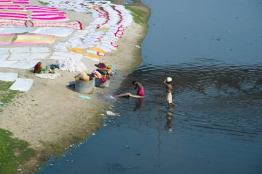 Agra, Hindistan - 15 Şubat 2018: Kimliği belirsiz insanlar Yanuma Agra nehrinin kıyısında sıcak güneşte yıkandıktan sonra bez kurutuyorlar 