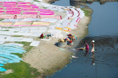 Agra, Hindistan - 15 Şubat 2018: Kimliği belirsiz insanlar Yanuma Agra nehrinin kıyısında sıcak güneşte yıkandıktan sonra bez kurutuyorlar 