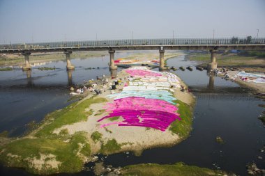 Agra, India - February 15, 2018: Unidentified people Drying cloth after washing in the hot sun on banks of River Yanuma Agra India  clipart