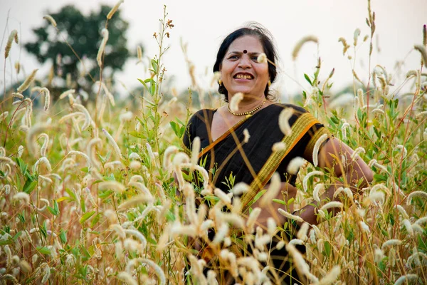 Beautiful happy Indian woman in sari at field and enjoying nature.