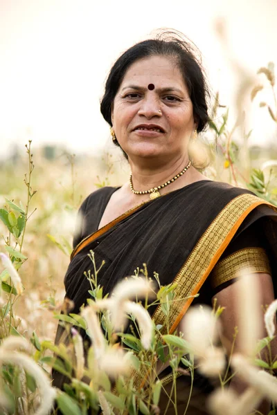 Beautiful happy Indian woman in sari at field and enjoying nature.