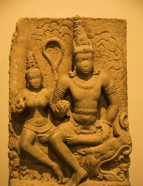An ancient Indian sculpture of the Hindu god and goddess carved in stone.