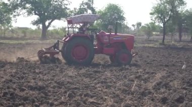 NASHIK, MAHARASHTRA, INDIA 8 HAZİRAN 2020: Kimliği belirsiz traktörlü çiftçi traktör ekimi için arazi hazırlıyor.