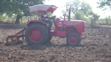 NASHIK, MAHARASHTRA, INDIA 8 HAZİRAN 2020: Kimliği belirsiz traktörlü çiftçi traktör ekimi için arazi hazırlıyor.