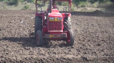 NASHIK, MAHARASHTRA, INDIA 8 HAZİRAN 2020: Kimliği belirsiz traktörlü çiftçi traktör ekimi için arazi hazırlıyor.