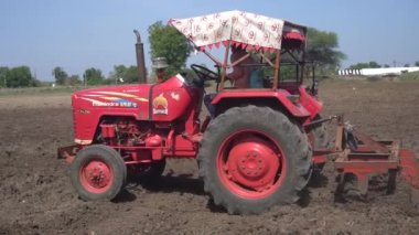 NASHIK, MAHARASHTRA, INDIA 8 HAZİRAN 2020: Kimliği belirsiz traktörlü çiftçi traktör ekimi için arazi hazırlıyor.