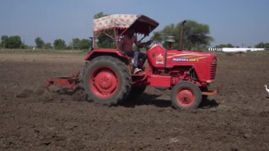 NASHIK, MAHARASHTRA, INDIA 8 HAZİRAN 2020: Kimliği belirsiz traktörlü çiftçi traktör ekimi için arazi hazırlıyor.