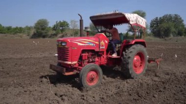 NASHIK, MAHARASHTRA, INDIA 8 HAZİRAN 2020: Kimliği belirsiz traktörlü çiftçi traktör ekimi için arazi hazırlıyor.