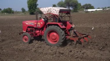 NASHIK, MAHARASHTRA, INDIA 8 HAZİRAN 2020: Kimliği belirsiz traktörlü çiftçi traktör ekimi için arazi hazırlıyor.