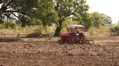 NASHIK, MAHARASHTRA, INDIA 8 HAZİRAN 2020: Kimliği belirsiz traktörlü çiftçi traktör ekimi için arazi hazırlıyor.