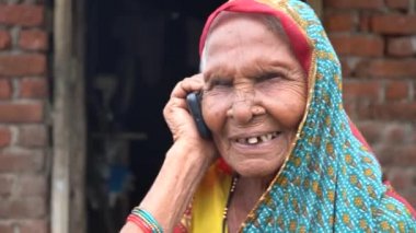 Köyde telefon kullanan Hintli yaşlı kırsal kadın.