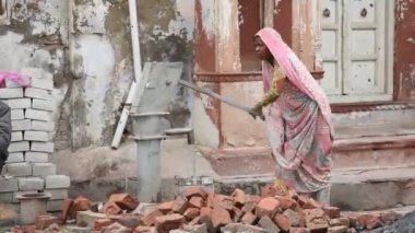 MATHURA, Hindistan - 10 Mart 2017: Kimliği belirsiz kadın el pompası veya insan gücüyle pompalanan Hindistan kırsal yaşam tarzı ile suyu derinlerden kaldırıyor.