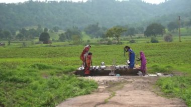 CHIKHALDARA, INDIA - 29 Haziran 2020: Tanımlanamayan Hintli kadınlar Maharashtra kırsalındaki kırsal kesimde geleneksel çömleklerde su taşıyorlar.
