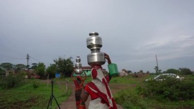 CHIKHALDARA, INDIA - 29 Haziran 2020: Tanımlanamayan Hintli kadınlar Maharashtra kırsalındaki kırsal kesimde geleneksel çömleklerde su taşıyorlar.