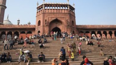 DELHI, Hindistan - 13 Şubat 2018: Jama Mescidi Camii merdivenlerinde birçok insan oturuyor, Jama Mescidi Delhi 'nin en ünlü simgelerinden biri..